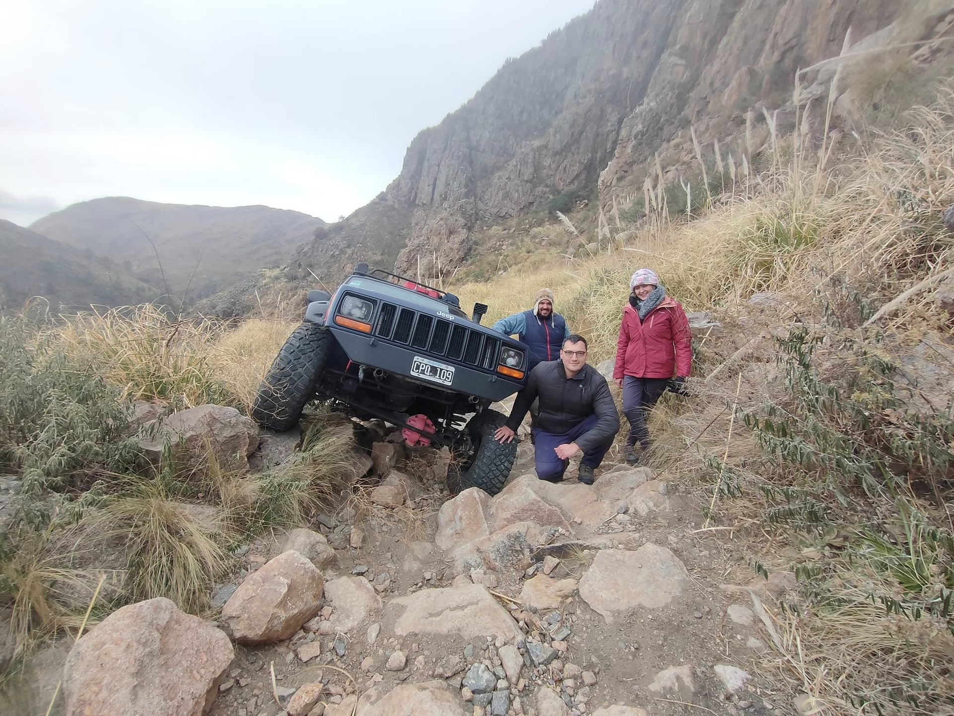 Grupo de viajeros junto a un Jeep Cherokee en un sendero de montaña