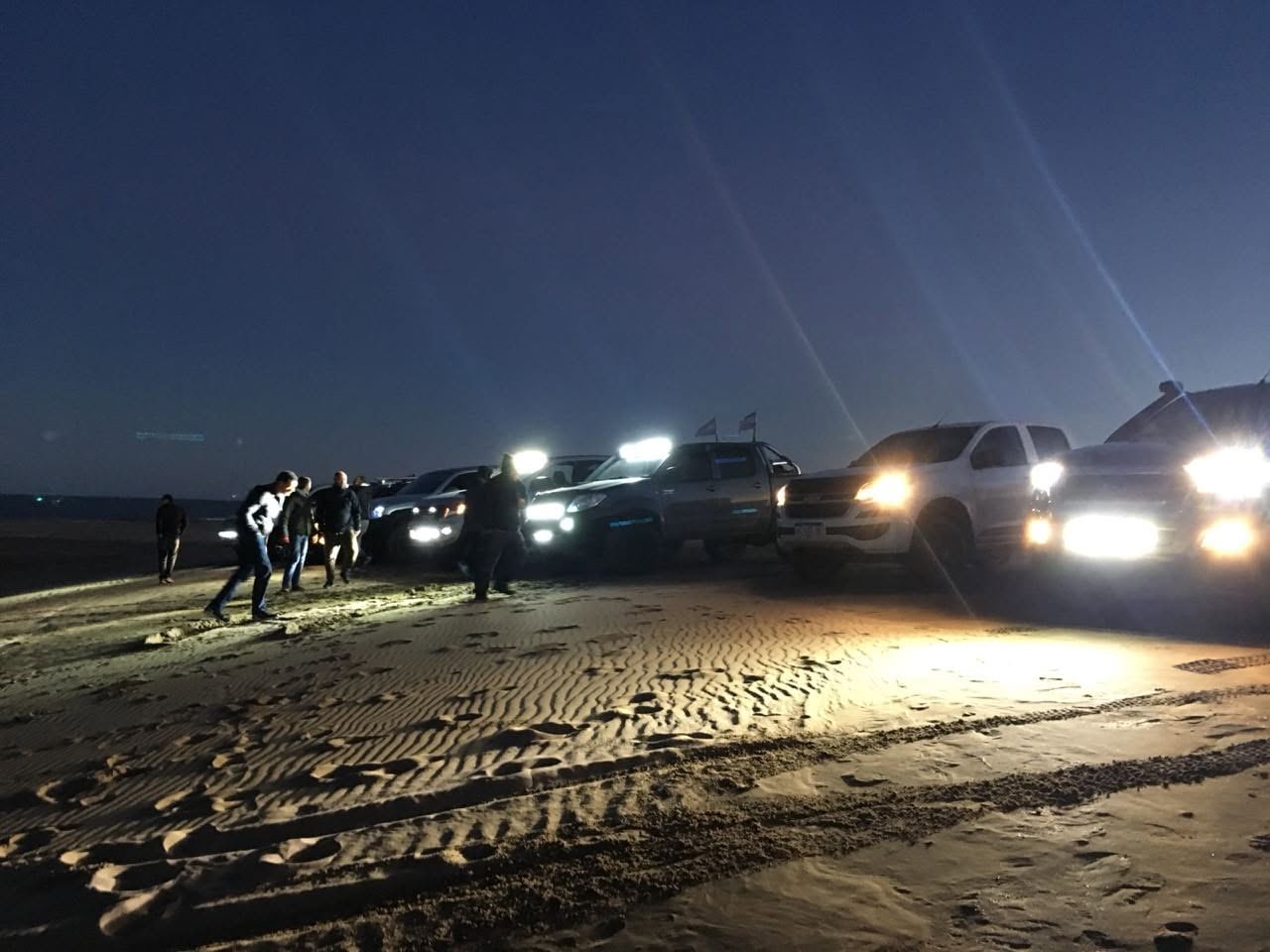 Encuentro de camionetas con sus luces encendidas durante una travesía nocturna en la arena